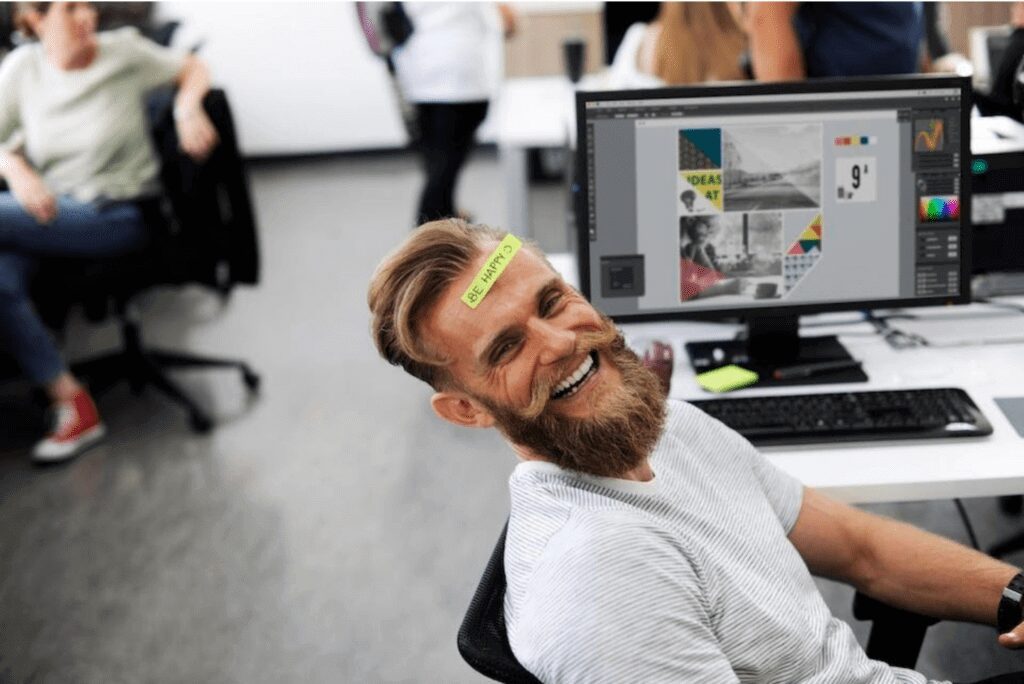 Happy employee having a sticky note written BE HAPPY on his face