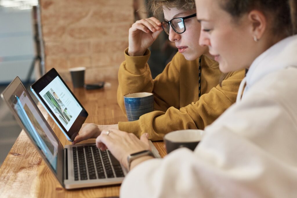 Young female IT engineers working with laptop and coffee cups infront of them on working desk.