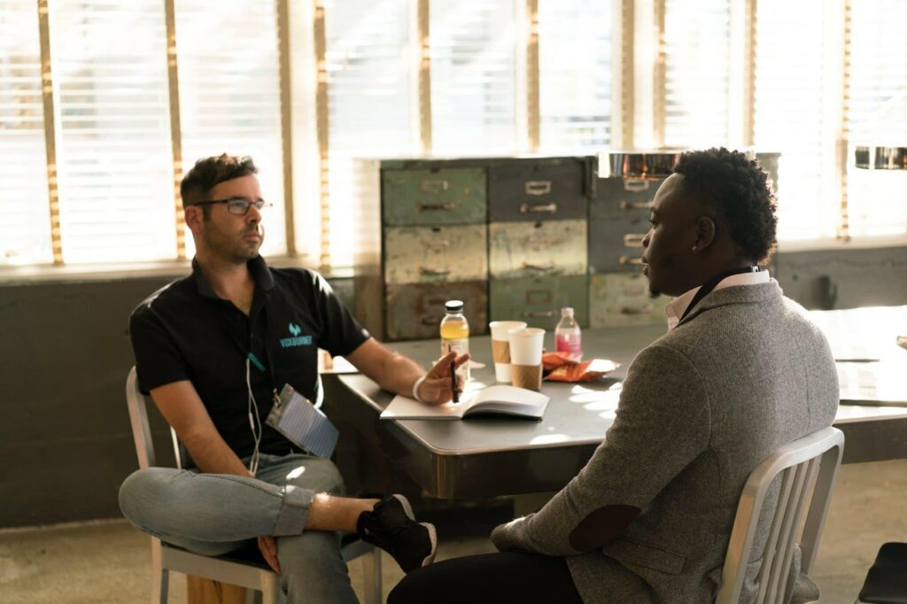 Black guy and white guy talking on hiring procedure in canteen