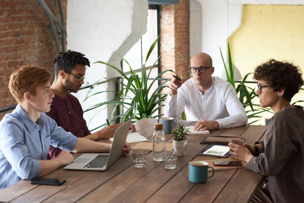 Group of 4 IT people sitting & discussing on Low Code uses for small businesses