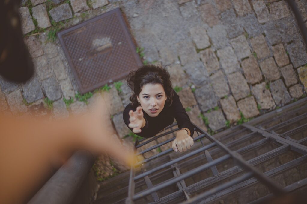 top view of a woman giving hand to pull up another woman climbing ladder