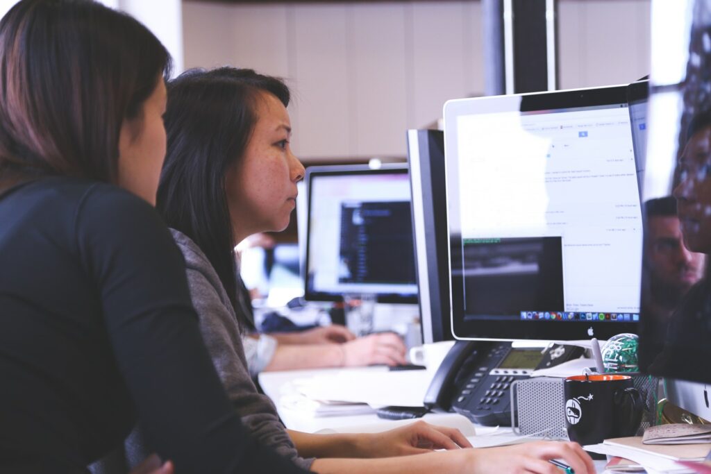 two women working on computer identifying low code development platforms