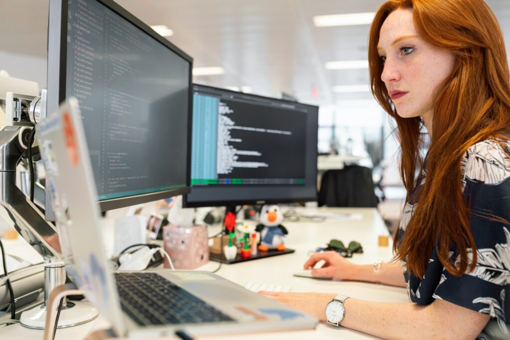 a woman working on laptop analysing low code development platform
