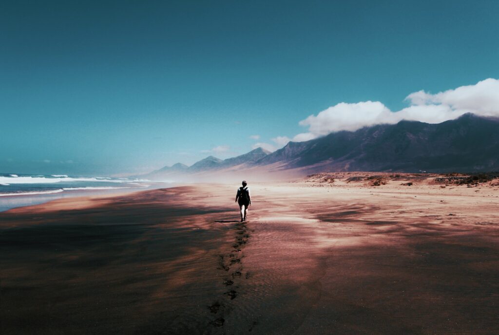 Woman walking on sea shore leaving footprints