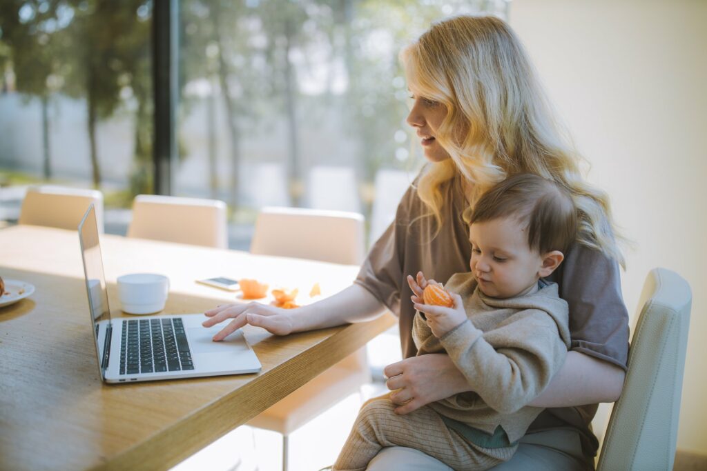 A woman with a kid working on the laptop