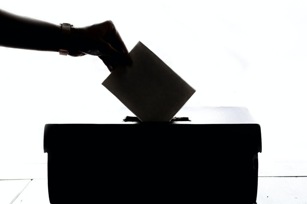 person dropping election ballot into box