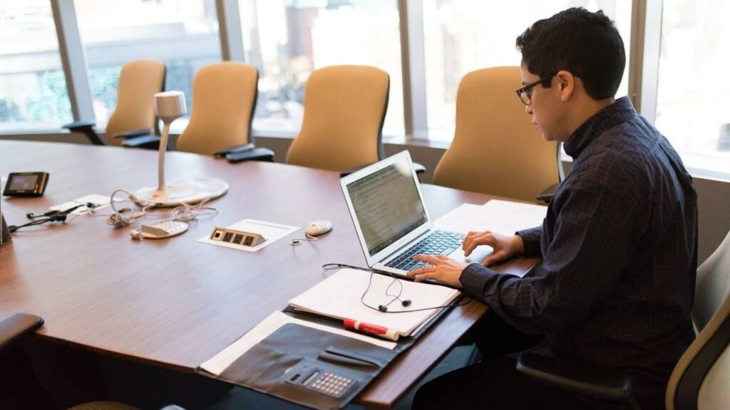 IT engineer working with laptop in conference room.