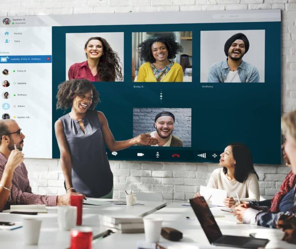 group of employees in conference room collaboratively working with virtual team on video call.