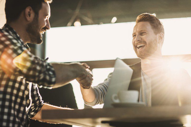 Happy employees smiling and shaking hands after a successful hiring process. 