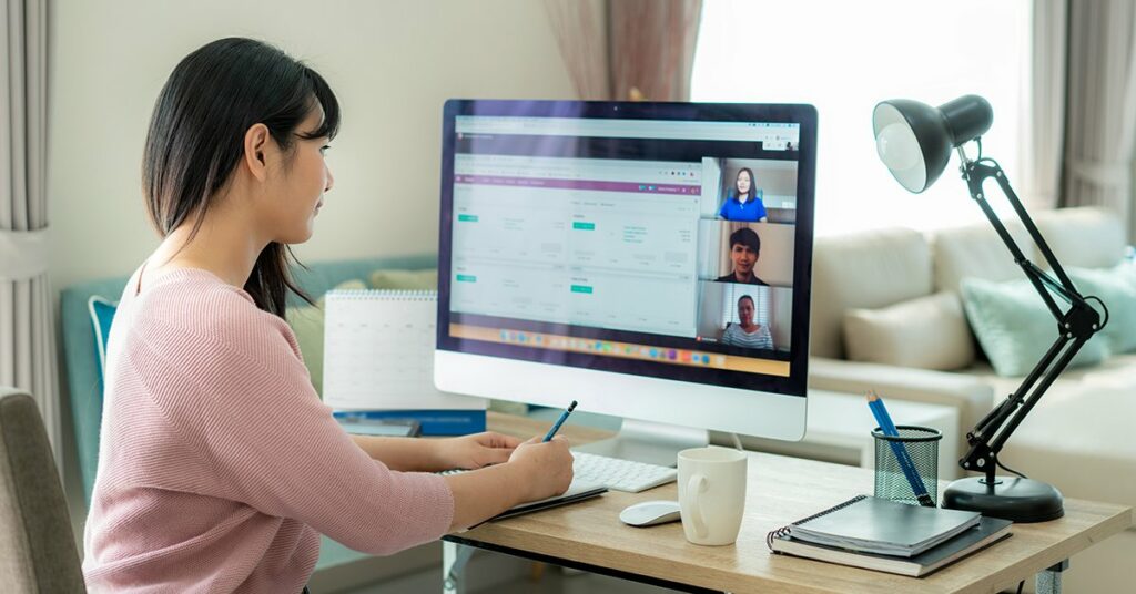 A woman looking at the monitor and talking to candidates online.