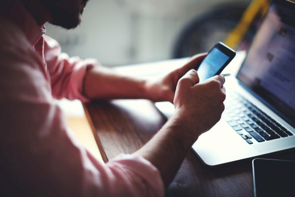 employee working on laptop while using mobile