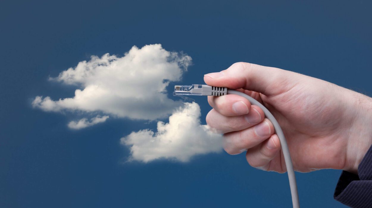 employee hand holding cable and connecting to clouds in sky.