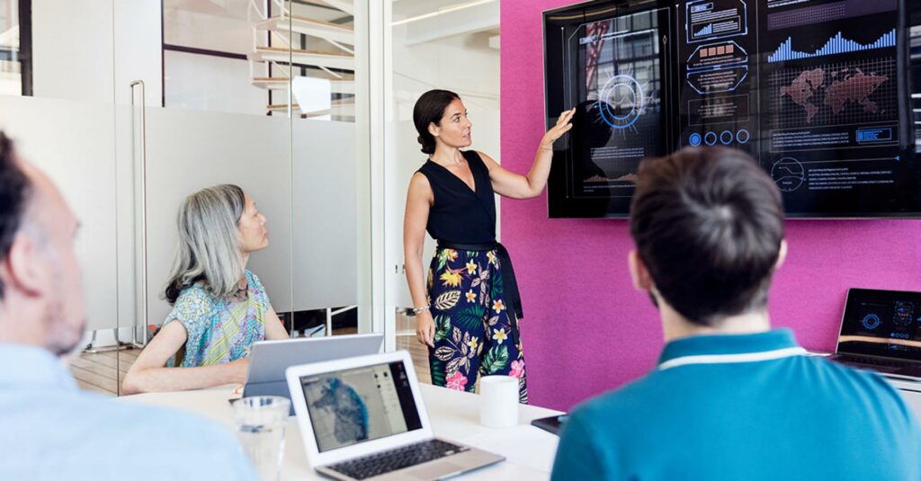 One women is giving presentation on edge computing and three people sitting and listening to her