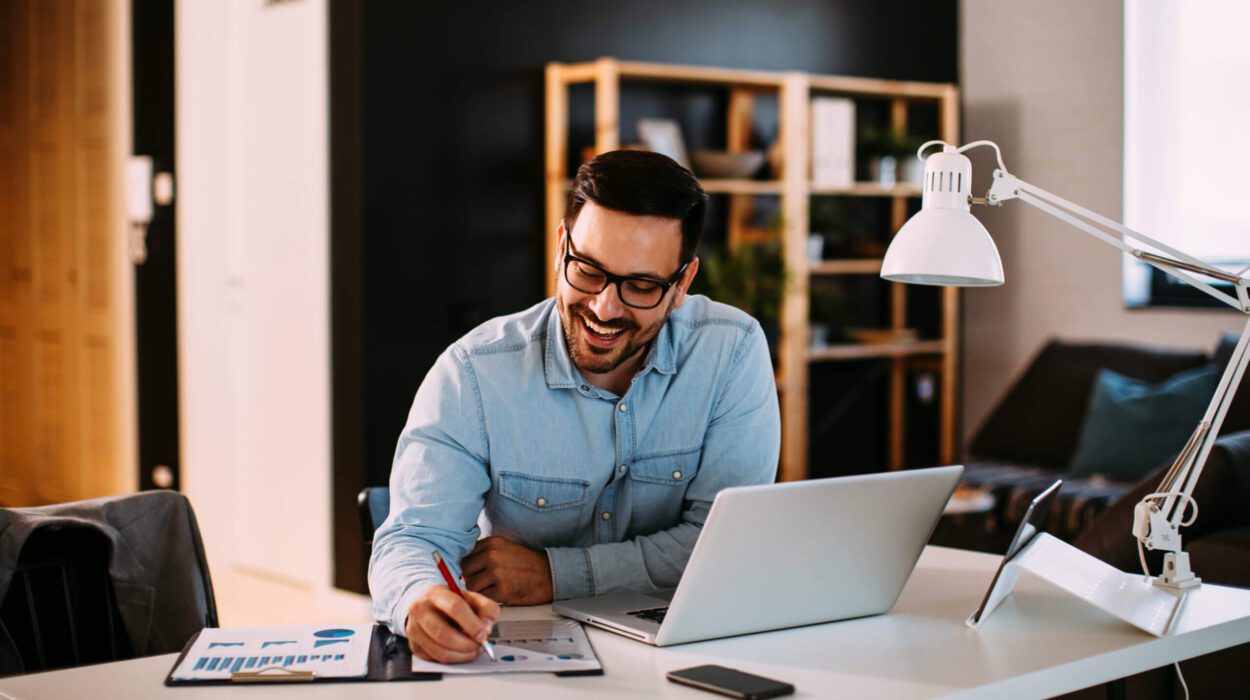 Young businessman working at home with laptop and papers on desk