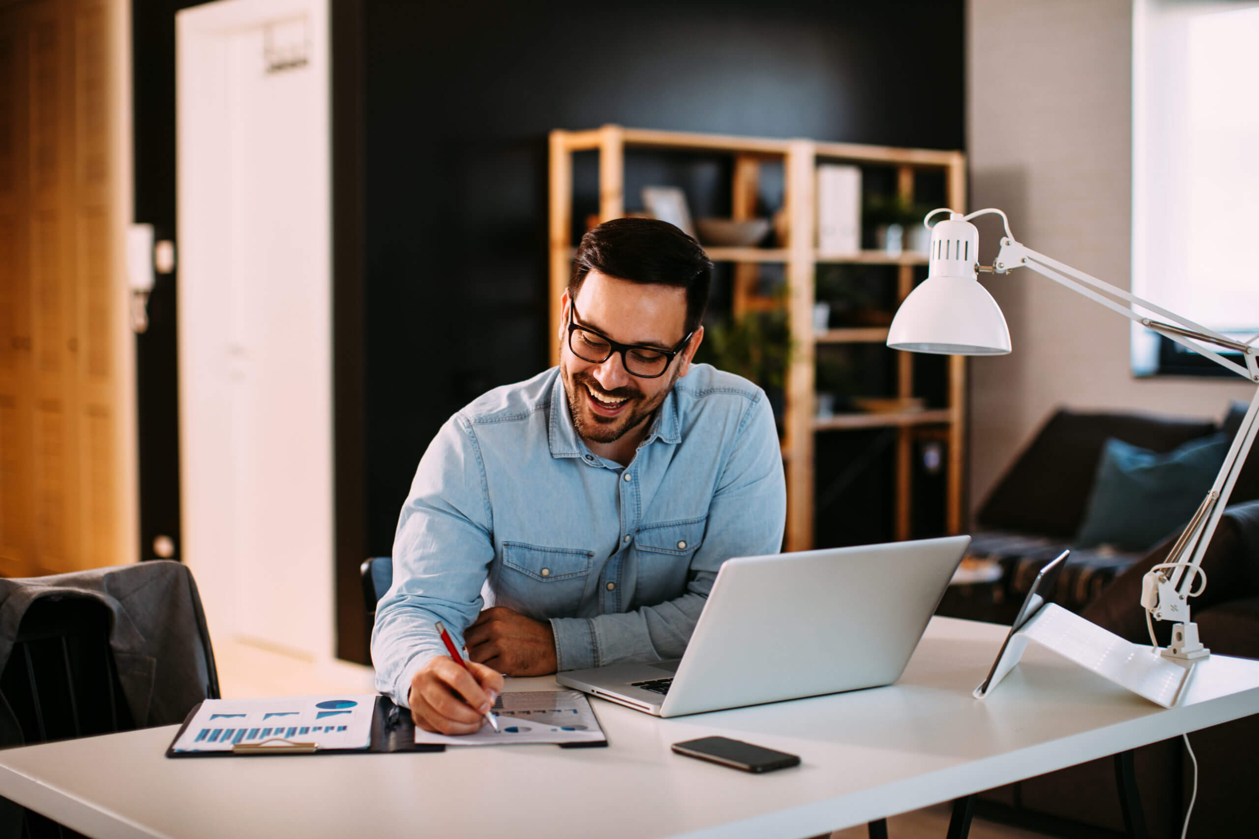 Young businessman working at home with laptop and papers on desk