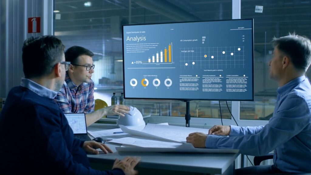 Three man looking at big screen showing analytics and discussing artificial intelligence in business 