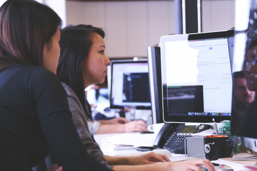 Female IT employees working on Edge AI platform with desktop from office.