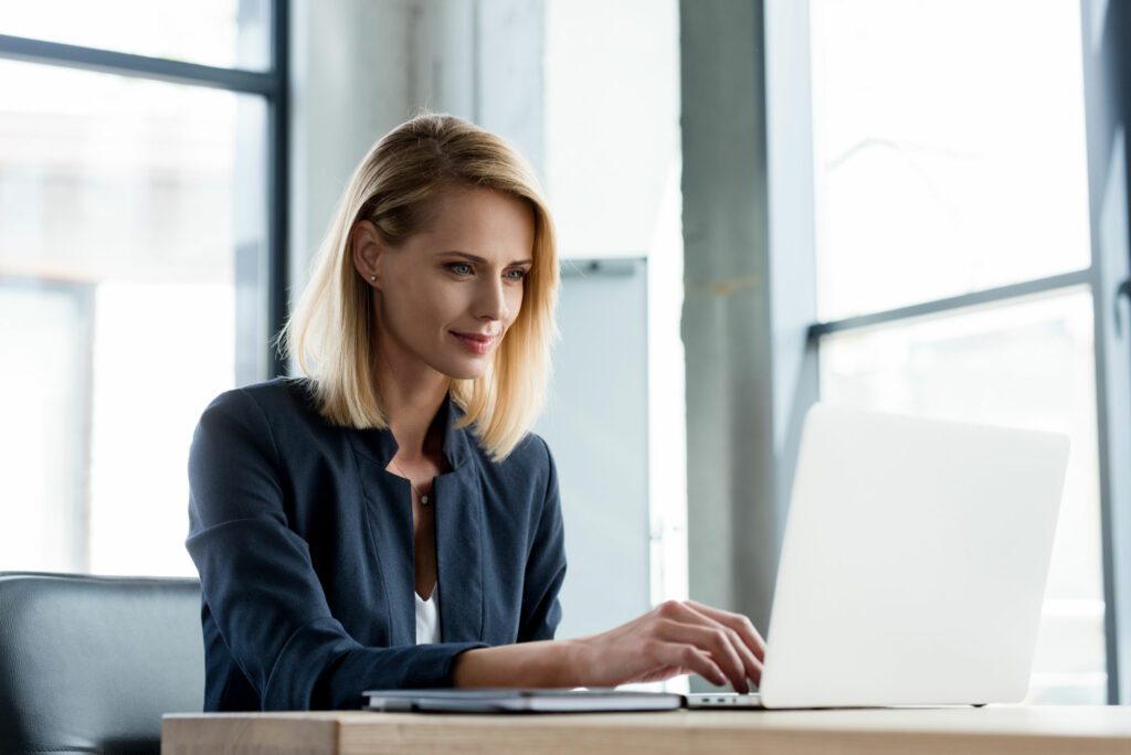 Young female IT employee working with laptop on AI programming
