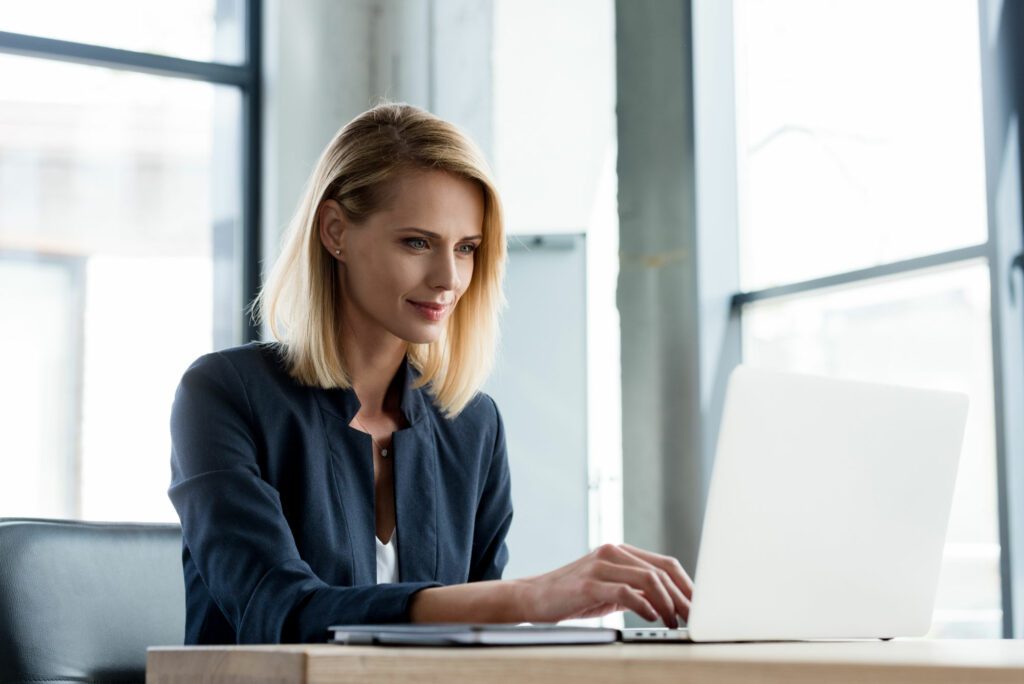 Young female IT employee working with laptop on AI programming 