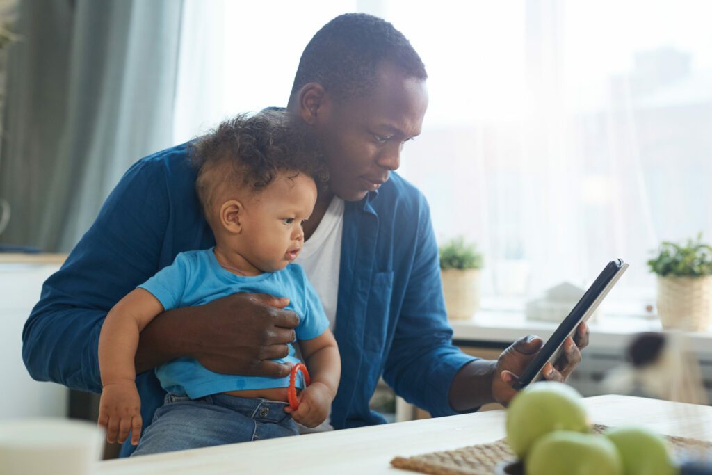 man with a toddler talking to his doctor on the phone holding baby in hand