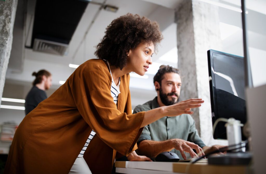 Young female IT engineer helping coworker to understand how to reduce operational cost techniques