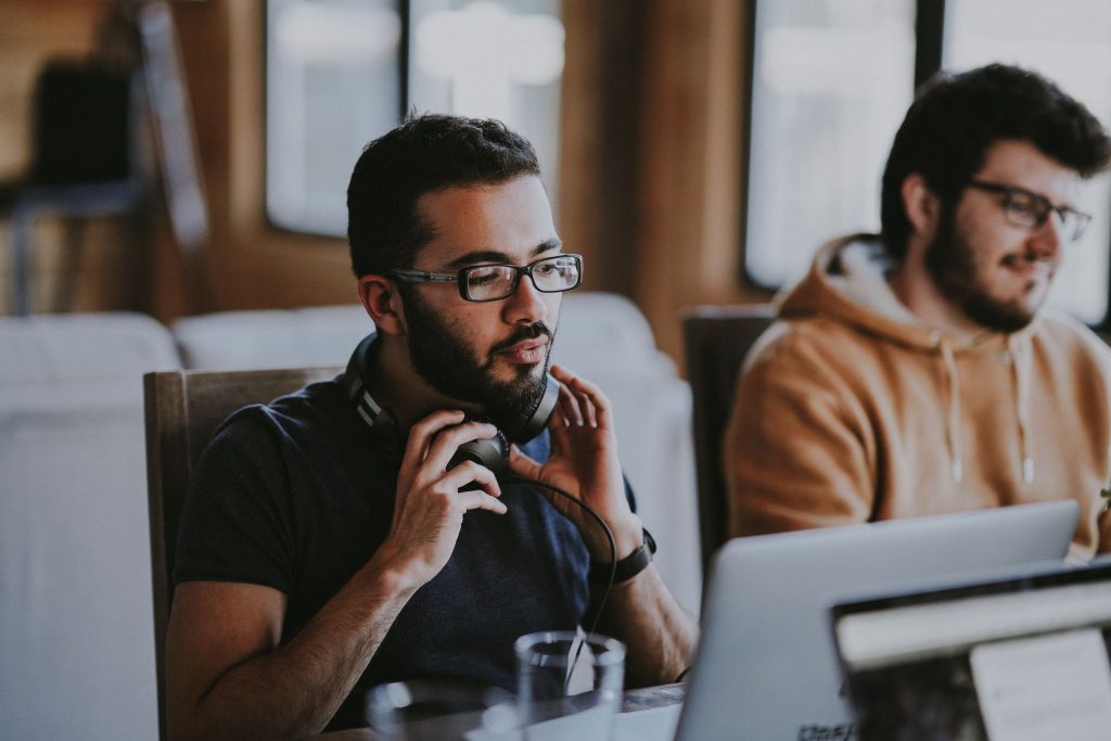 Two men working on the computer. One man is with headphone