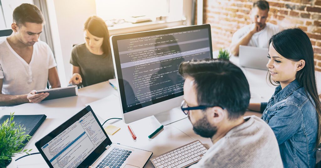 men and women working on laptops creating a plan to prevent cyber attacks