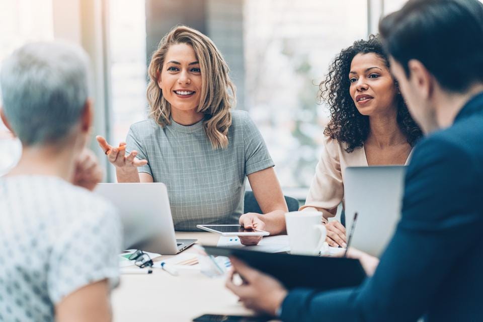 Women and man sitting and talking to each other about intelligent automation. One woman is holding an ipad