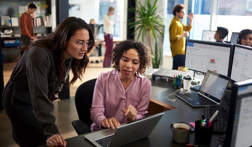 two women looking at the laptop screen and discussing digital transformation with microsoft